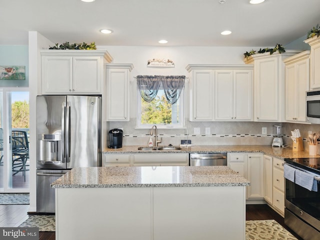 kitchen with dark wood-type flooring, a sink, appliances with stainless steel finishes, decorative backsplash, and light stone countertops