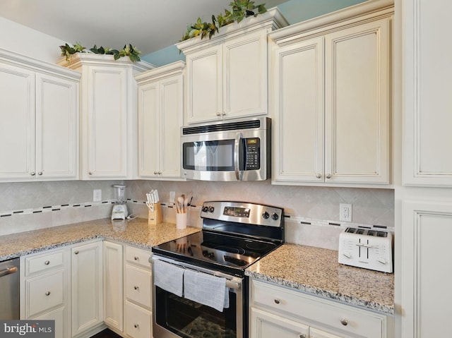 kitchen featuring light stone countertops, tasteful backsplash, appliances with stainless steel finishes, and cream cabinetry