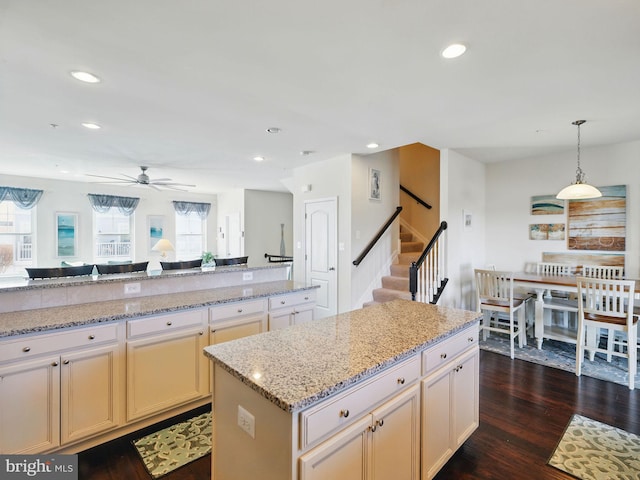 kitchen featuring light stone counters, a kitchen island, dark wood finished floors, recessed lighting, and hanging light fixtures