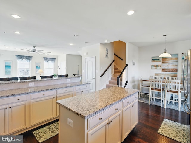 kitchen featuring decorative light fixtures, dark wood finished floors, a center island, recessed lighting, and light stone countertops