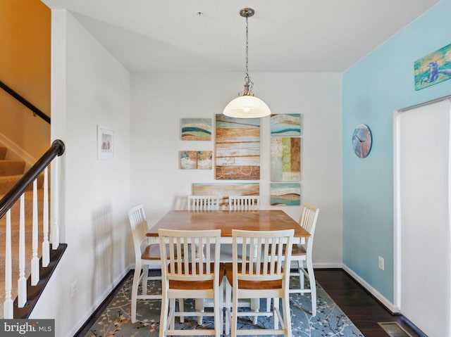 dining room featuring stairway, baseboards, visible vents, and wood finished floors