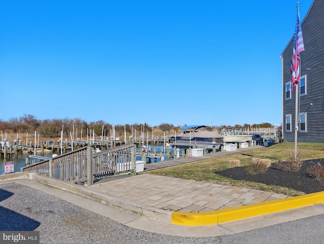 dock area with boat lift, a lawn, and a water view