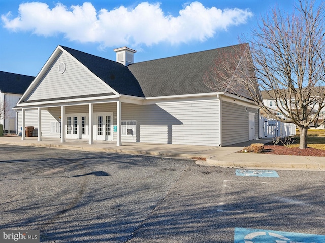 view of front of property with french doors and roof with shingles