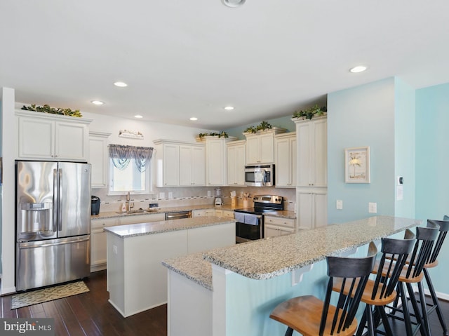 kitchen featuring a kitchen island, stainless steel appliances, decorative backsplash, and a sink