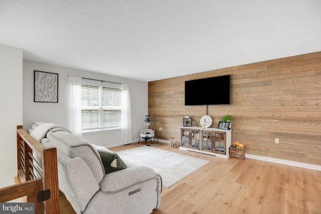 living area with baseboards, wooden walls, and wood finished floors