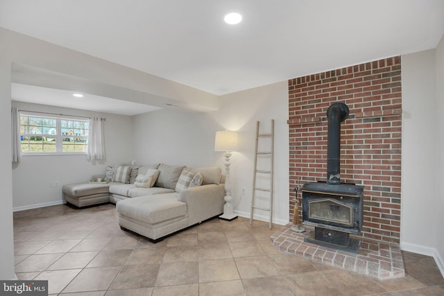 living room with tile patterned flooring, a wood stove, and baseboards