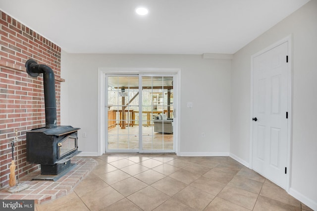 unfurnished living room with tile patterned flooring, a wood stove, and baseboards