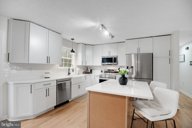 kitchen with a sink, backsplash, a kitchen island, and appliances with stainless steel finishes