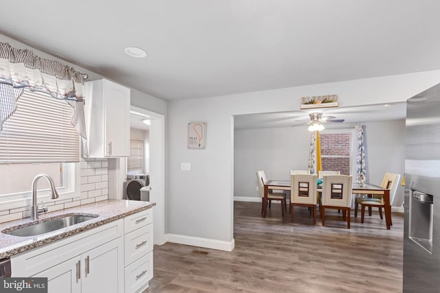 kitchen with backsplash, washer / dryer, light wood-style floors, and a sink