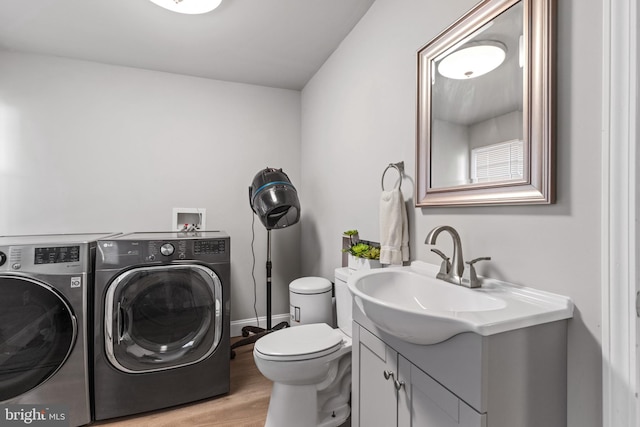 laundry room with baseboards, washing machine and dryer, laundry area, light wood-style floors, and a sink