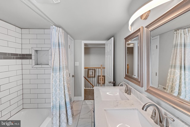 full bath featuring double vanity, marble finish floor, shower / bath combo with shower curtain, and a sink