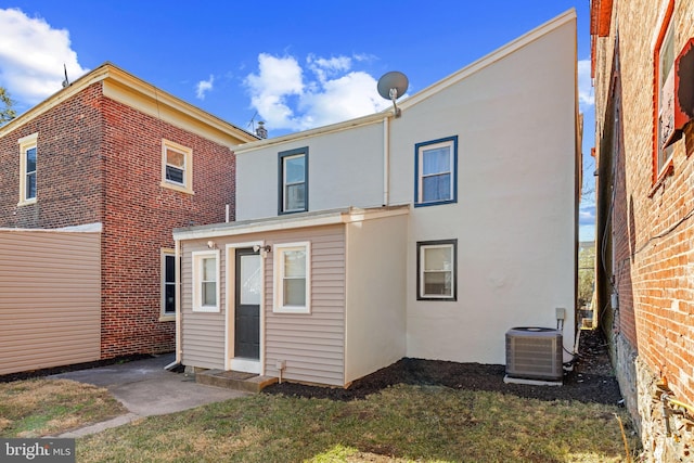 back of house featuring cooling unit, a yard, and stucco siding