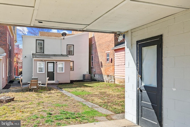 back of property with a carport, cooling unit, and a yard