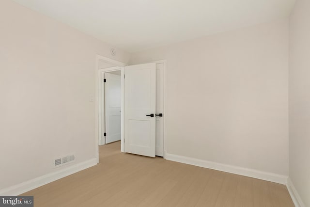 spare room featuring light wood-style floors, visible vents, and baseboards