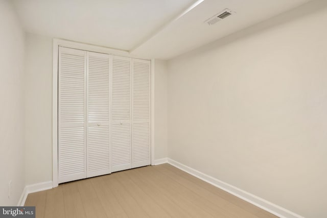 unfurnished bedroom featuring light wood-style floors, visible vents, a closet, and baseboards