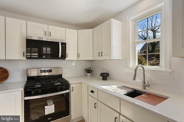 kitchen with a sink, white cabinets, a healthy amount of sunlight, and stainless steel appliances