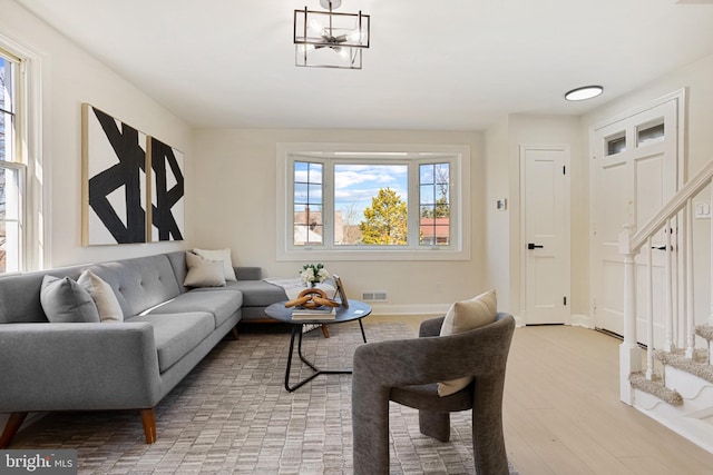 living area with light wood-type flooring, visible vents, baseboards, and stairs