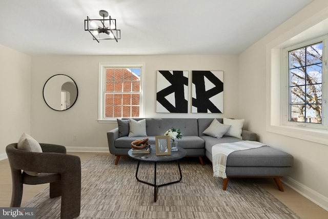 living room featuring a notable chandelier, a healthy amount of sunlight, and baseboards