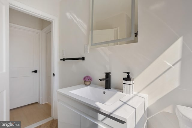 bathroom with toilet, wood finished floors, and vanity