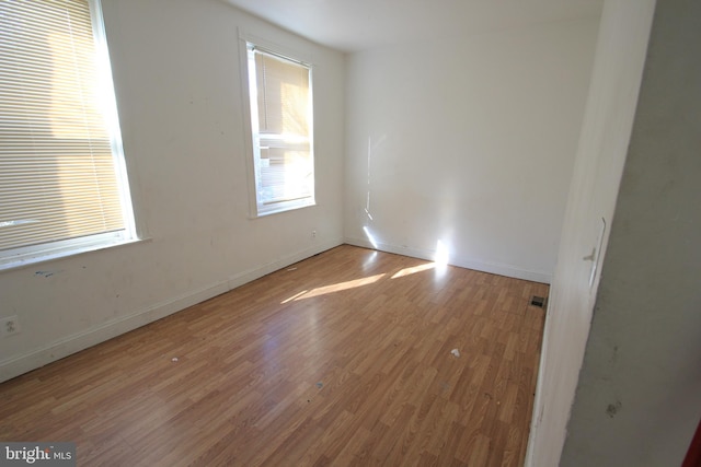 spare room featuring baseboards and wood finished floors