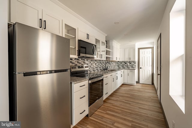 kitchen with backsplash, appliances with stainless steel finishes, white cabinetry, and a sink