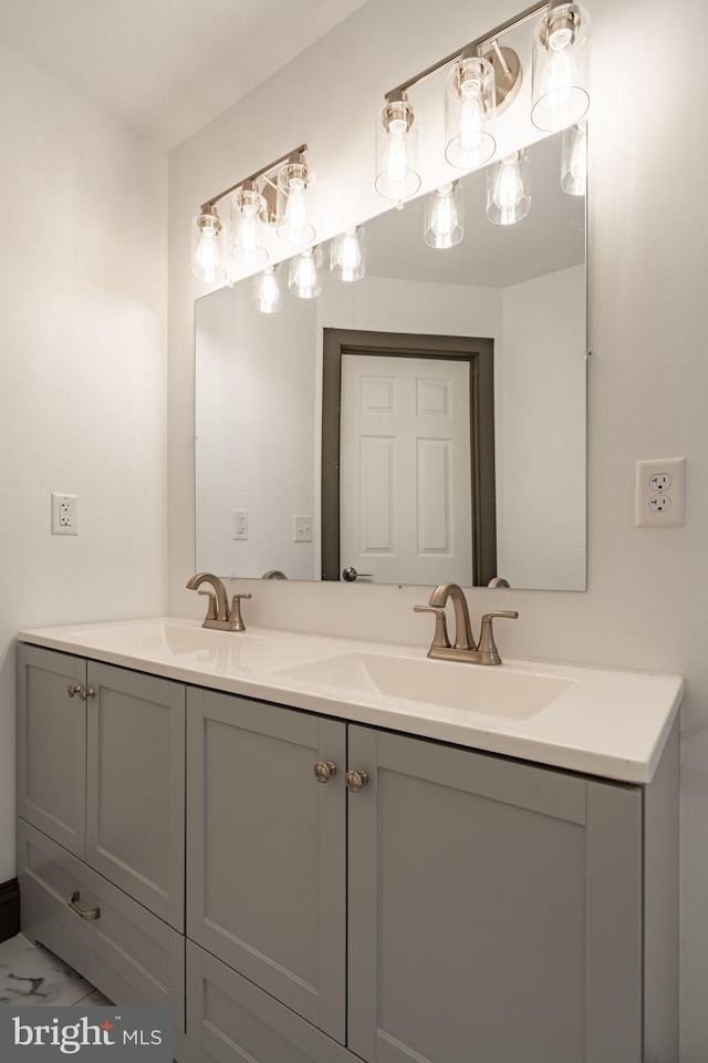 full bath with double vanity, marble finish floor, and a sink