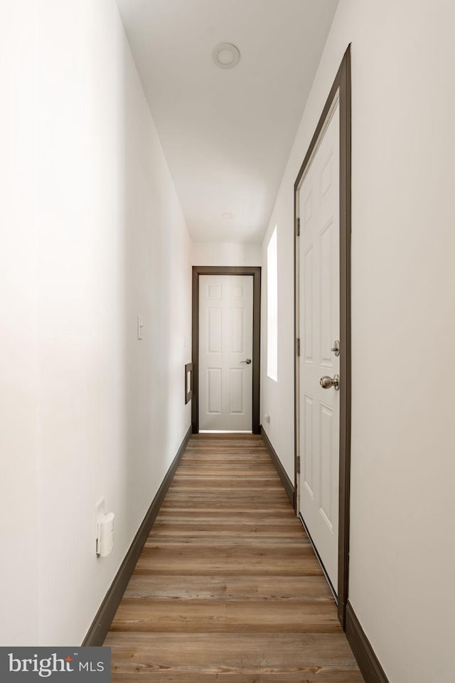 hall with light wood-type flooring and baseboards