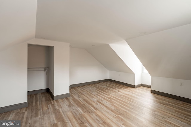 bonus room featuring vaulted ceiling, light wood-style floors, and baseboards