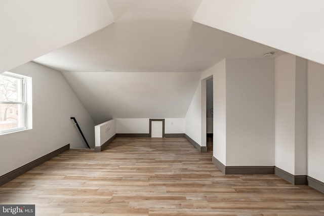 additional living space with light wood-type flooring, lofted ceiling, and baseboards