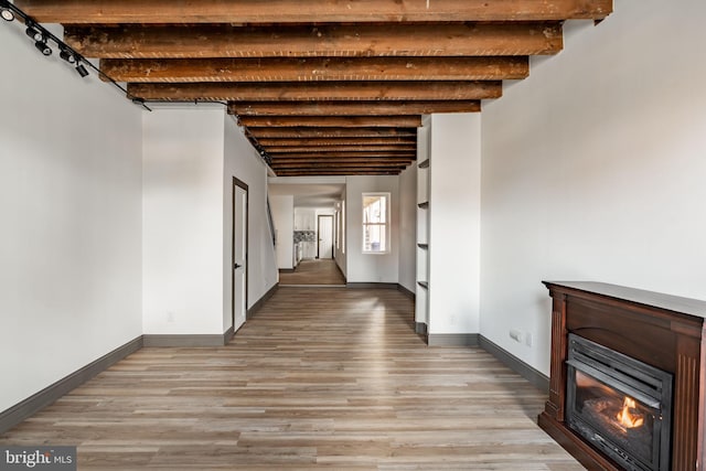 hall with beam ceiling, light wood finished floors, and baseboards