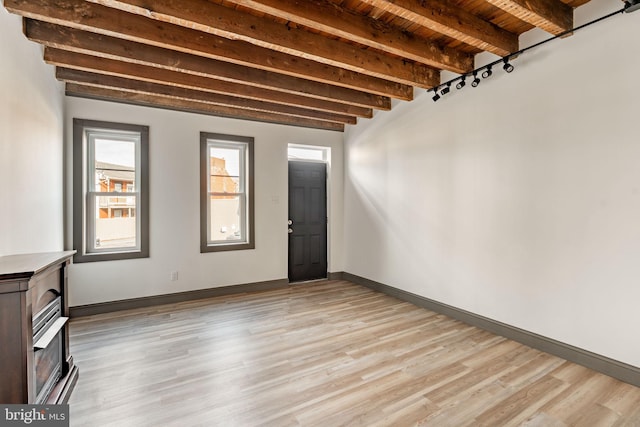 interior space with beam ceiling, wooden ceiling, baseboards, and light wood-style floors