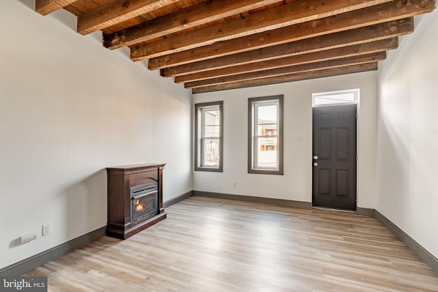 unfurnished living room featuring beam ceiling, light wood-style flooring, wooden ceiling, and baseboards