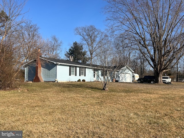 view of front of house featuring a garage, a chimney, and a front lawn