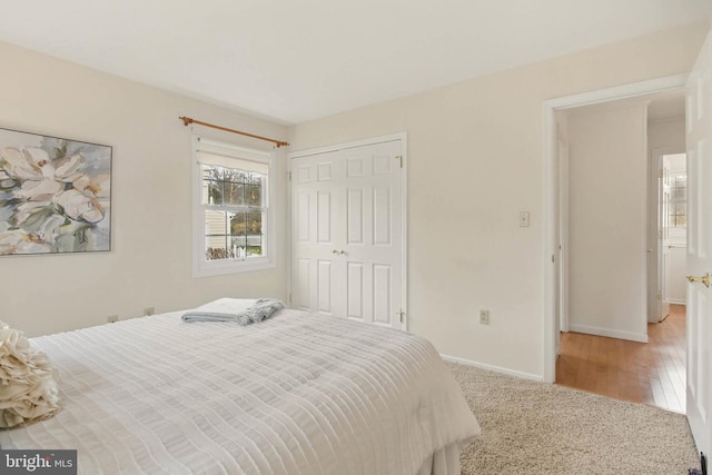 carpeted bedroom with a closet and baseboards