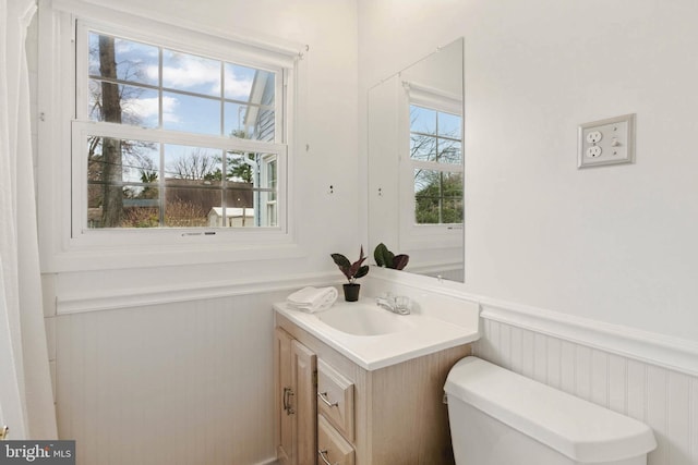 bathroom with a wainscoted wall, toilet, and vanity