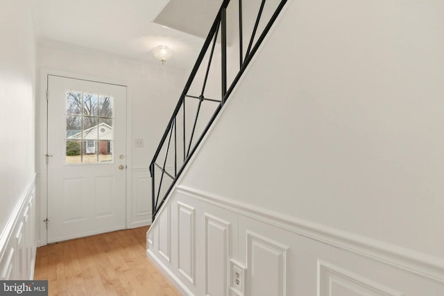 interior space featuring stairway, a decorative wall, light wood-style floors, and wainscoting