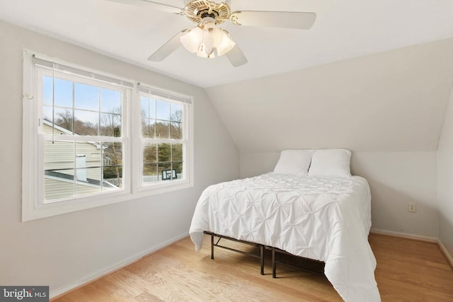 bedroom with vaulted ceiling, ceiling fan, baseboards, and wood finished floors