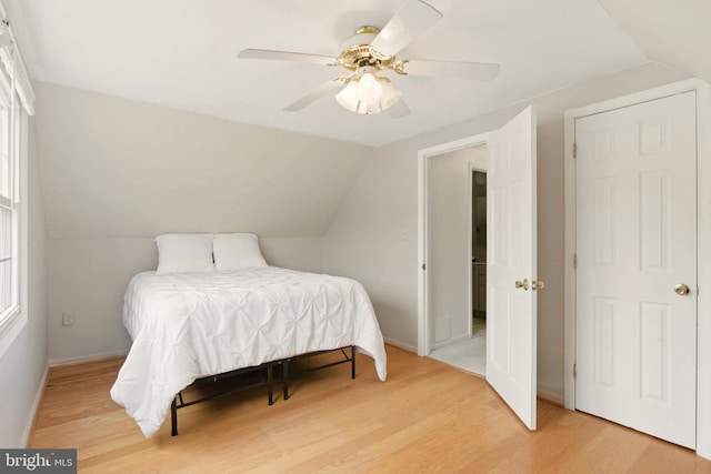 bedroom featuring baseboards, light wood-style flooring, a ceiling fan, and vaulted ceiling