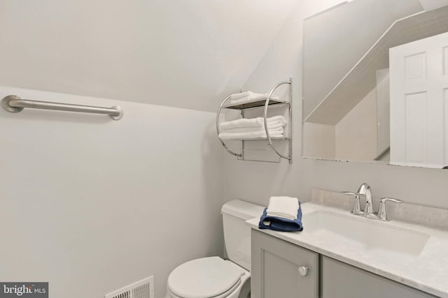 bathroom featuring visible vents, toilet, vanity, and lofted ceiling