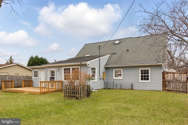 rear view of property with a yard, a shingled roof, a deck, and fence