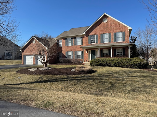 view of front of home featuring a front lawn, a porch, brick siding, and aphalt driveway