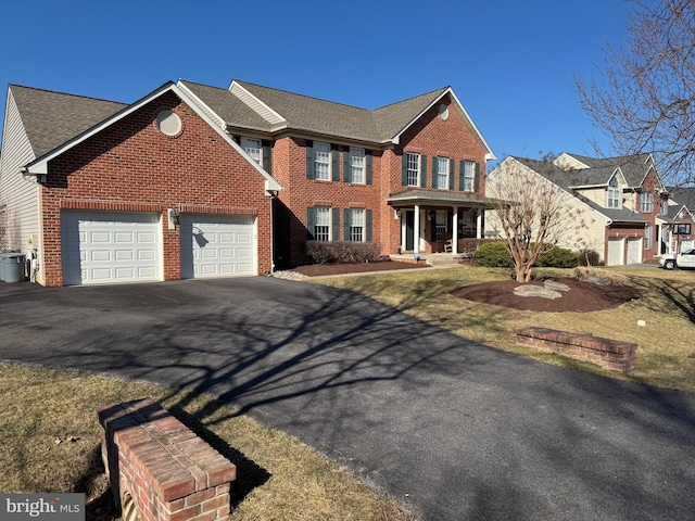 view of front of home featuring aphalt driveway, brick siding, and a shingled roof