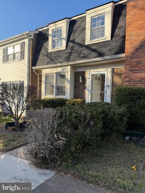 view of front of house with brick siding and roof with shingles