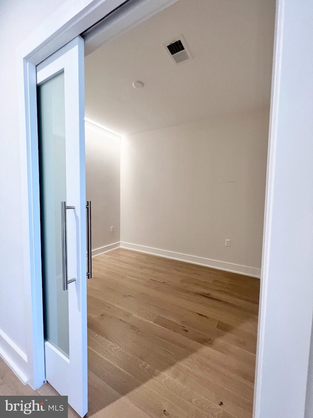 hallway with visible vents, baseboards, and wood finished floors