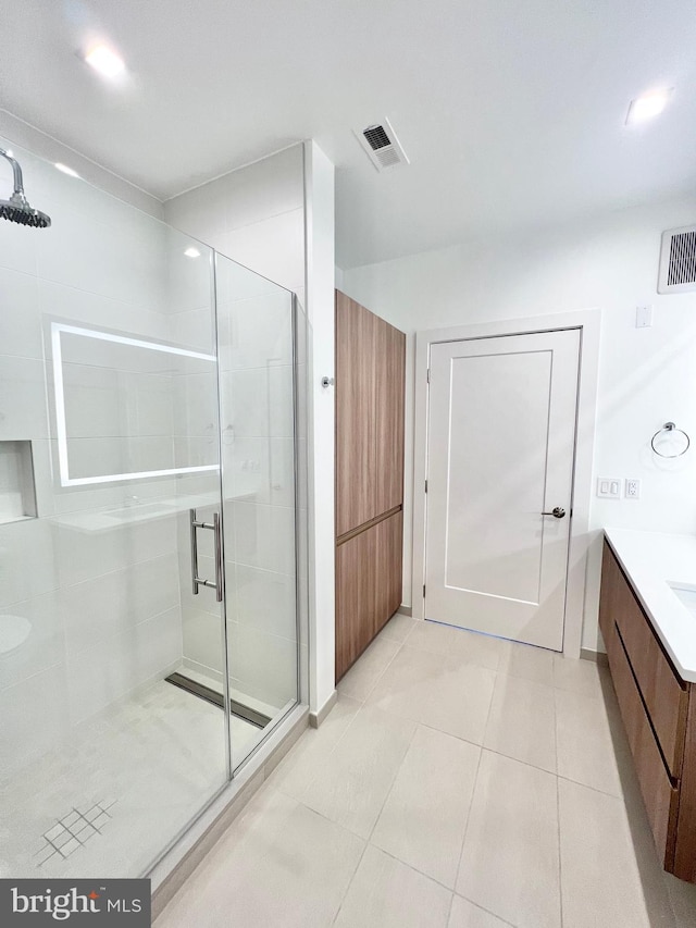 full bathroom featuring tile patterned flooring, visible vents, a shower stall, and vanity