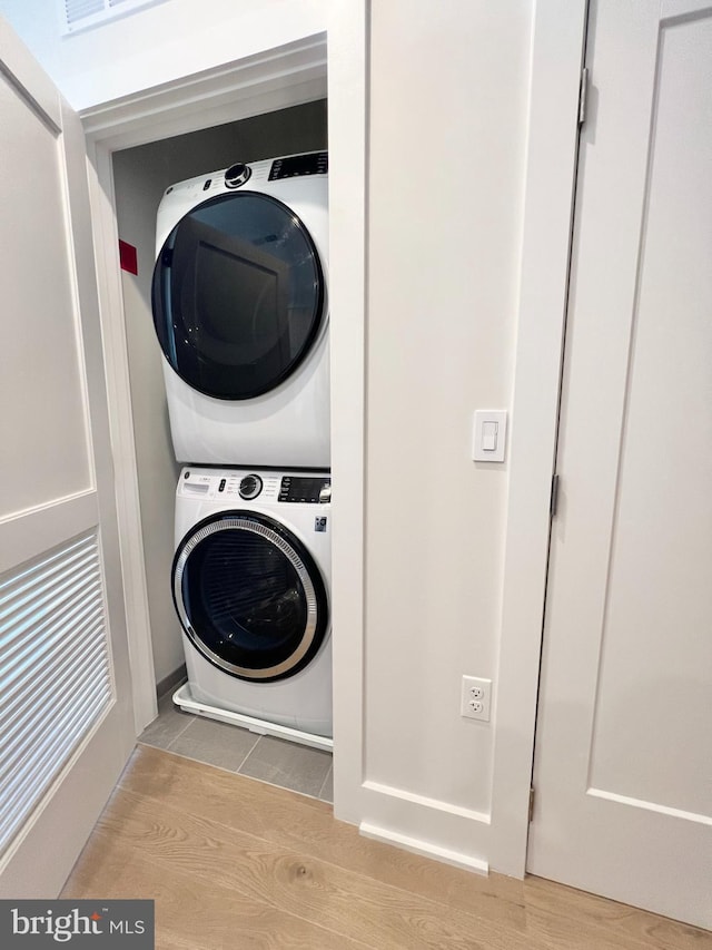 laundry area featuring laundry area, wood finished floors, and stacked washer and clothes dryer