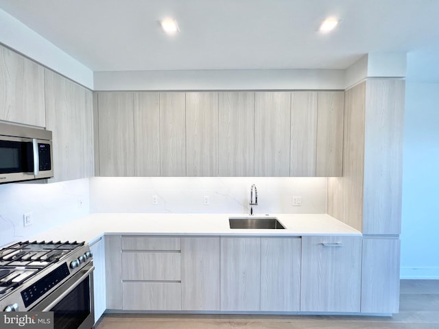 kitchen with a sink, stainless steel appliances, modern cabinets, and light countertops