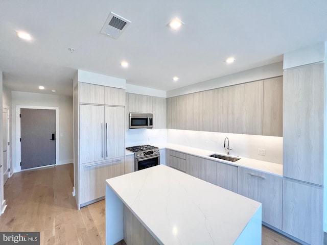 kitchen featuring visible vents, a center island, stainless steel appliances, modern cabinets, and a sink