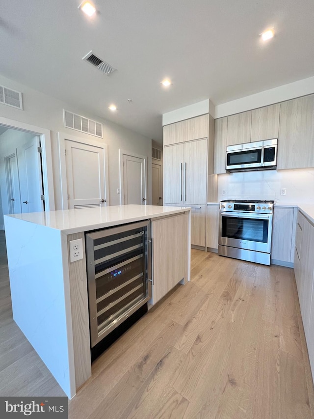 kitchen with beverage cooler, visible vents, stainless steel appliances, and modern cabinets