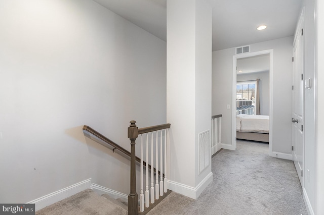 hall featuring an upstairs landing, visible vents, carpet, and baseboards